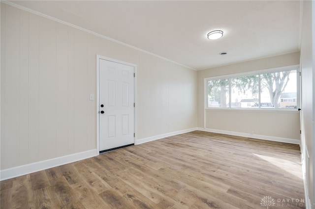 empty room with baseboards, wood finished floors, and crown molding