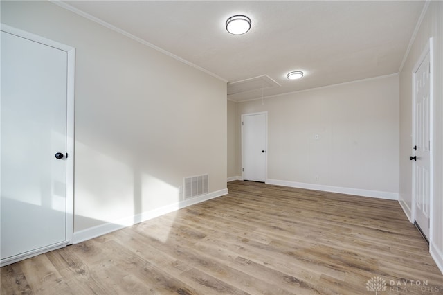 spare room with visible vents, wood finished floors, attic access, and crown molding