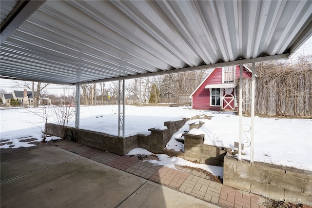 snow covered patio featuring an outdoor structure and fence