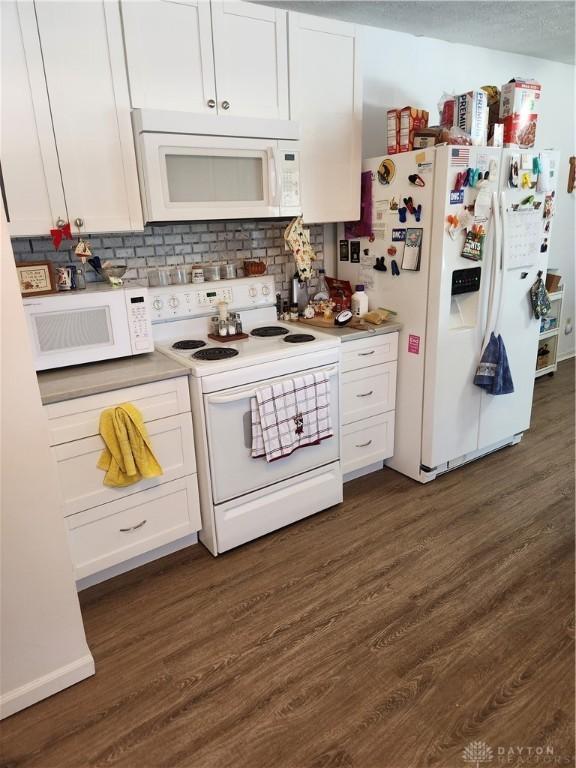 kitchen featuring white cabinetry, dark wood-type flooring, and white appliances