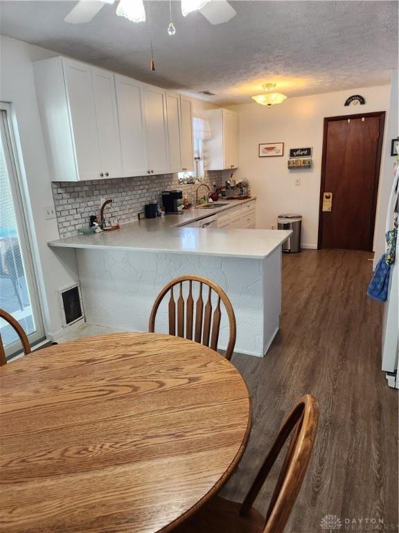 kitchen featuring ceiling fan, dark wood-type flooring, kitchen peninsula, and white cabinets