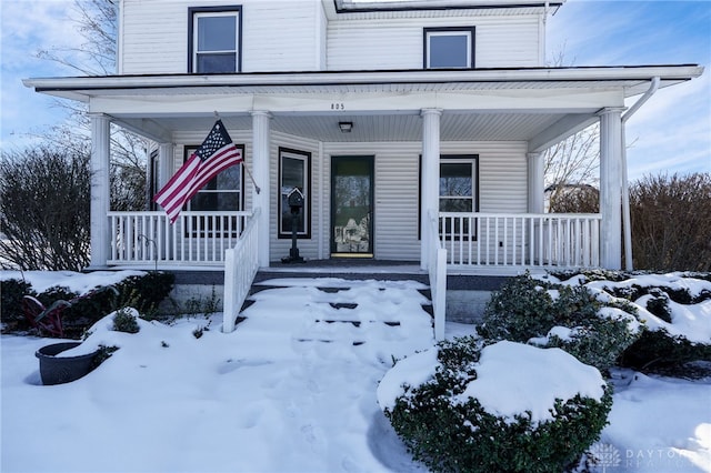 snow covered property entrance featuring a porch