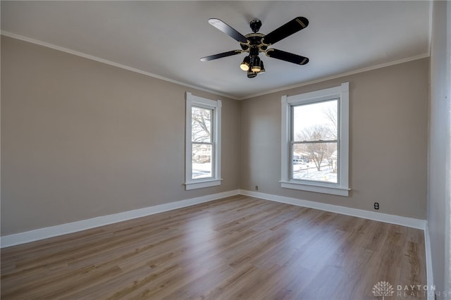 spare room with light wood finished floors, ornamental molding, and baseboards