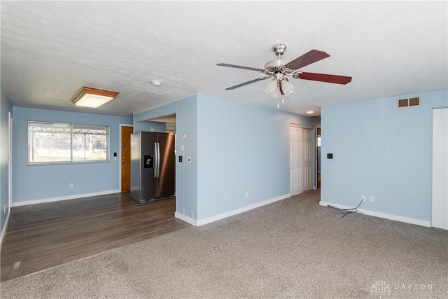 unfurnished room with ceiling fan, a textured ceiling, and dark colored carpet