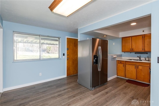 kitchen with dark wood-type flooring, stainless steel fridge, and sink