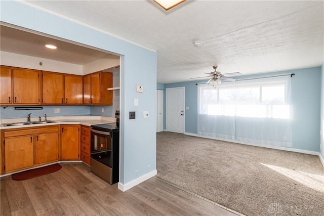 kitchen with sink, light hardwood / wood-style flooring, ceiling fan, range with electric stovetop, and a textured ceiling