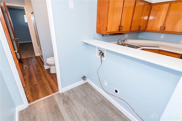 clothes washing area featuring sink, cabinets, light hardwood / wood-style flooring, hookup for a washing machine, and hookup for an electric dryer