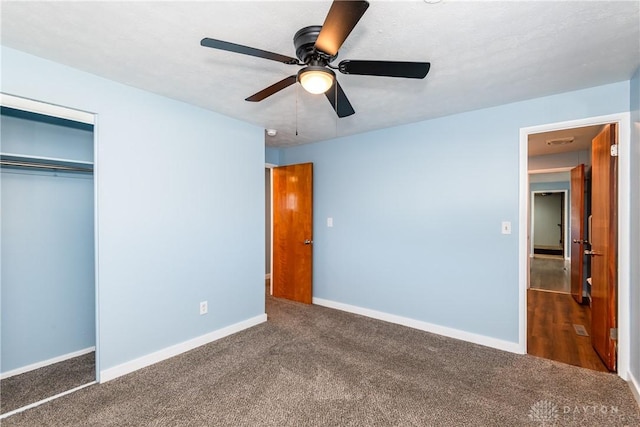 unfurnished bedroom featuring ceiling fan, dark carpet, and a closet