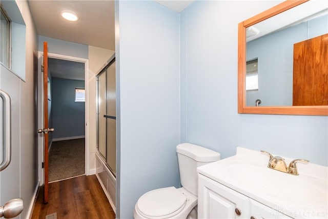 full bathroom with hardwood / wood-style flooring, vanity, toilet, and combined bath / shower with glass door