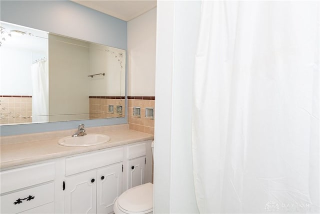 bathroom with vanity, toilet, and tile walls