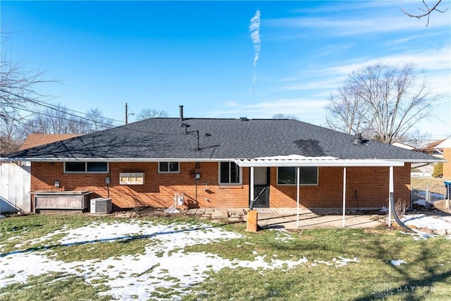 snow covered back of property featuring a hot tub and central air condition unit