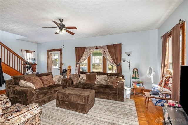 living room featuring ceiling fan, light hardwood / wood-style flooring, and a textured ceiling