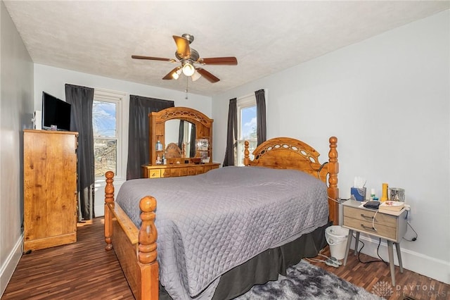 bedroom featuring ceiling fan, dark hardwood / wood-style flooring, and multiple windows