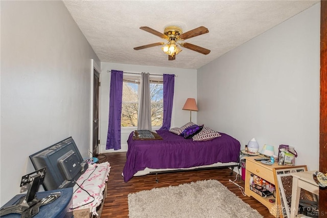 bedroom with ceiling fan, dark wood-type flooring, and a textured ceiling