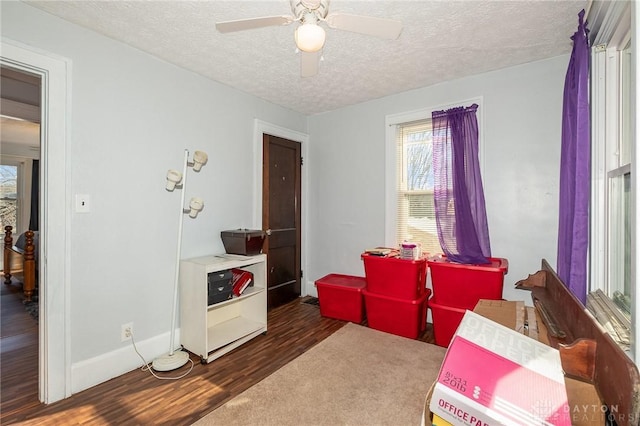 misc room with ceiling fan, dark hardwood / wood-style floors, and a textured ceiling