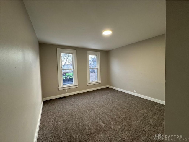 unfurnished room with dark colored carpet