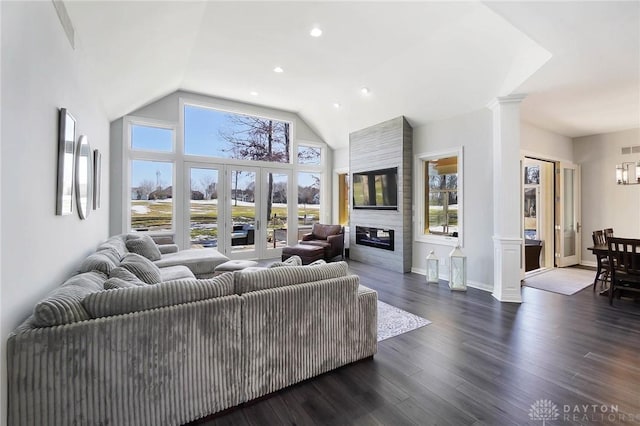 living room featuring dark wood-type flooring, high vaulted ceiling, a fireplace, and decorative columns