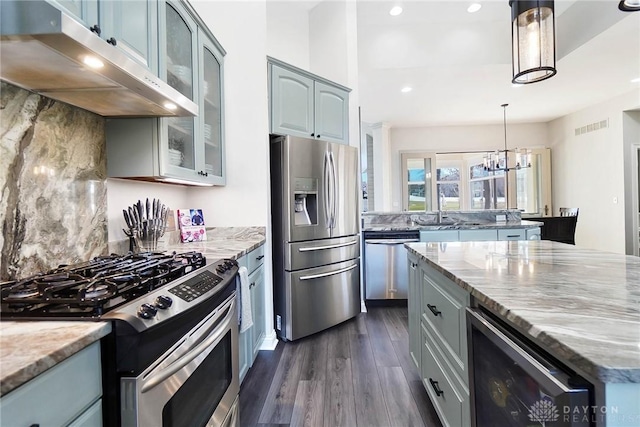 kitchen featuring wine cooler, stainless steel appliances, light stone countertops, and hanging light fixtures