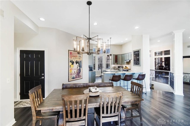 dining area with decorative columns, a chandelier, and dark hardwood / wood-style flooring