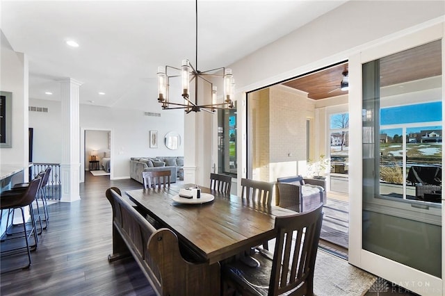 dining area with dark wood-type flooring, an inviting chandelier, and ornate columns