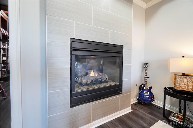 interior details with a tile fireplace, wood finished floors, crown molding, and baseboards