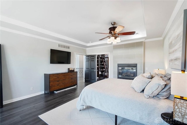 bedroom with dark wood-style floors, baseboards, a raised ceiling, and crown molding
