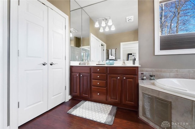 bathroom featuring vanity, tiled bath, and hardwood / wood-style floors