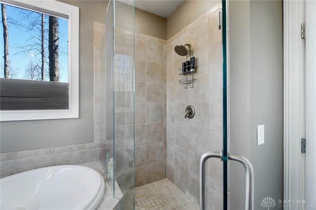 full bathroom with a stall shower and a bath