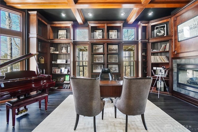 living area with dark hardwood / wood-style floors, beamed ceiling, a tiled fireplace, coffered ceiling, and built in shelves