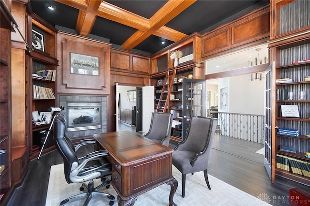 home office with hardwood / wood-style flooring, beam ceiling, coffered ceiling, built in shelves, and wood walls