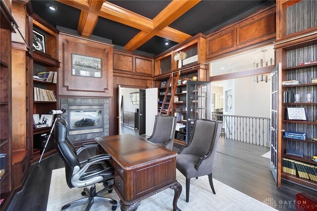 office space featuring wood finished floors, a fireplace, beamed ceiling, and coffered ceiling