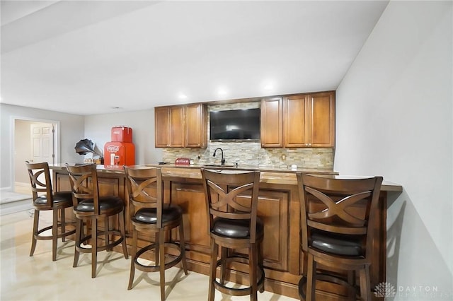 bar featuring tasteful backsplash and sink