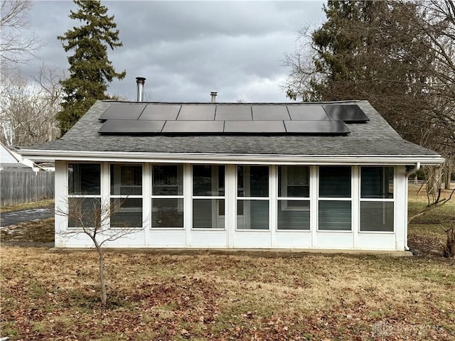 back of house with a sunroom, a yard, and solar panels