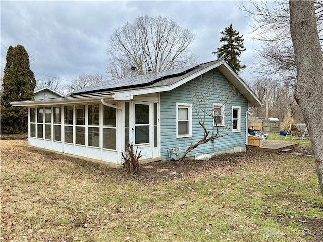 view of side of home with a lawn, a sunroom, and solar panels