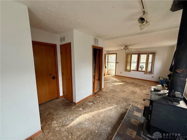 interior space featuring a textured ceiling, baseboards, and visible vents