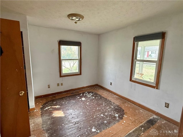 spare room with baseboards and a textured ceiling