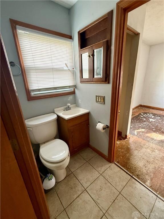 bathroom with toilet, vanity, tile patterned floors, and baseboards