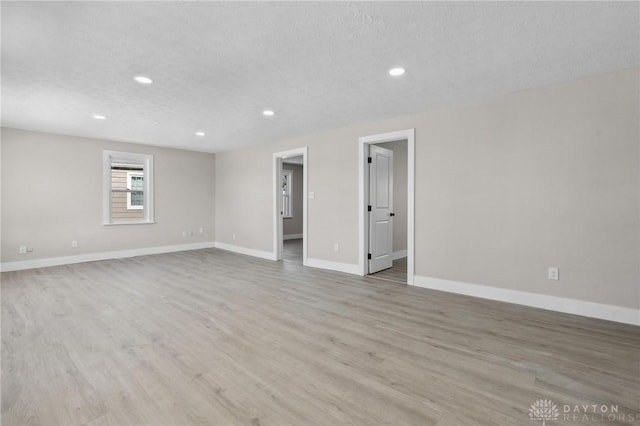 spare room with a textured ceiling and light wood-type flooring