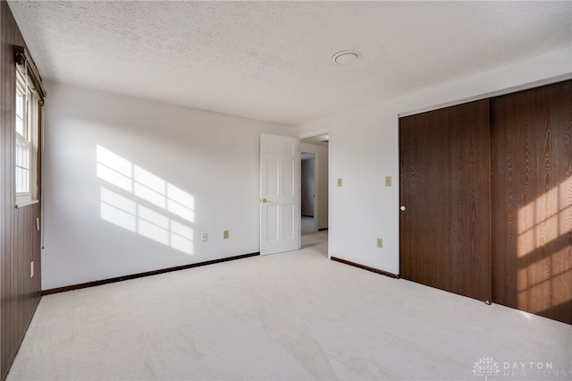 unfurnished bedroom featuring light colored carpet, a closet, and a textured ceiling