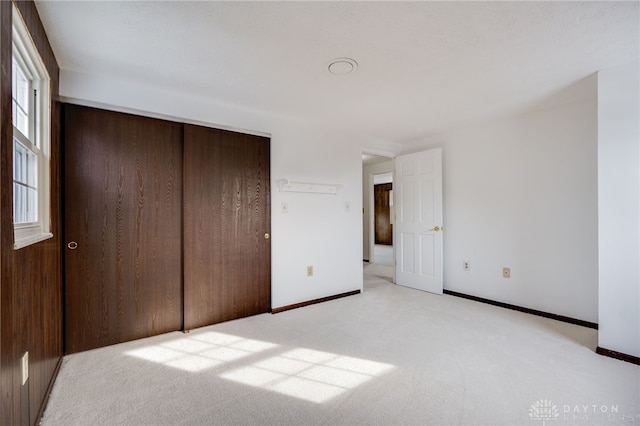 unfurnished bedroom featuring light colored carpet and a closet