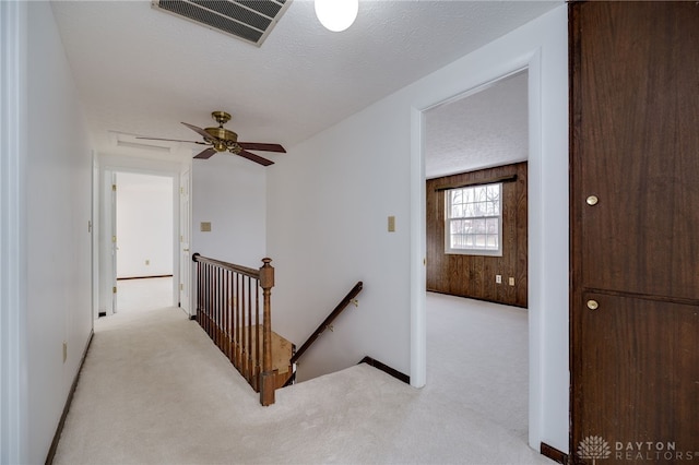 corridor with light colored carpet and a textured ceiling