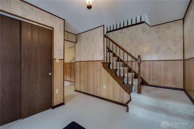 stairway with wooden walls and a textured ceiling