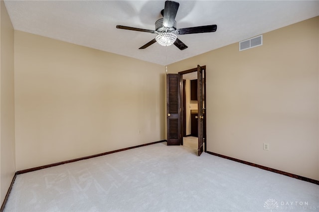 spare room with ceiling fan and light colored carpet