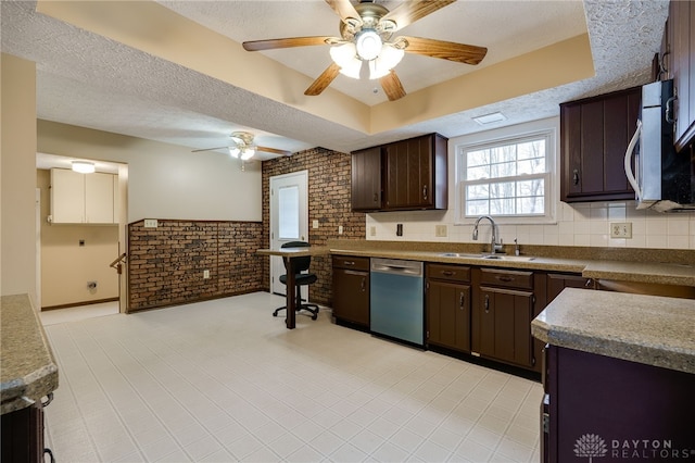 kitchen featuring stainless steel appliances, sink, dark brown cabinets, a textured ceiling, and brick wall