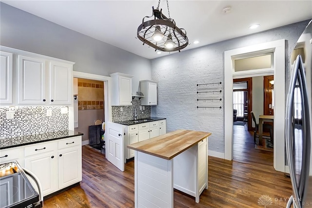 kitchen with white cabinetry, butcher block counters, pendant lighting, and stainless steel refrigerator