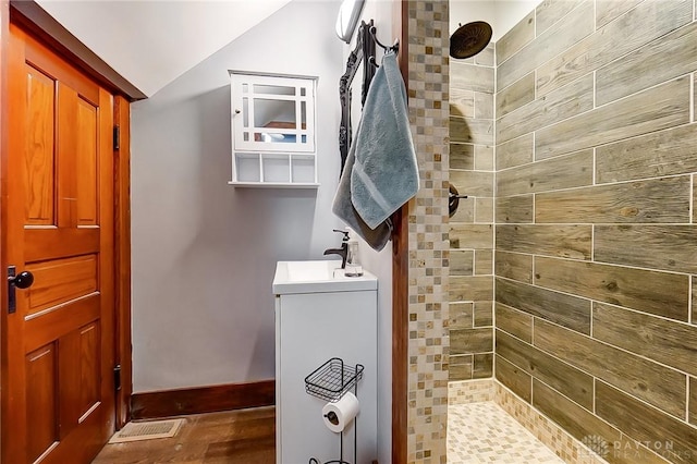 bathroom featuring lofted ceiling, sink, and tiled shower