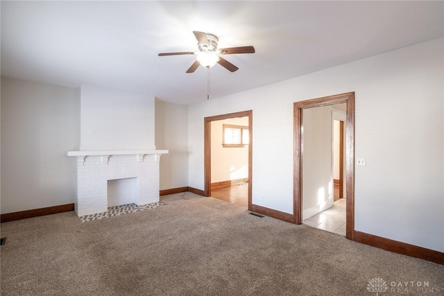 unfurnished living room with light carpet, a brick fireplace, and ceiling fan