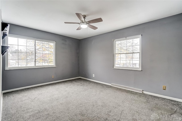 carpeted spare room with a baseboard radiator, a wealth of natural light, and ceiling fan