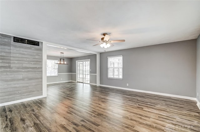 empty room with ceiling fan with notable chandelier and hardwood / wood-style floors