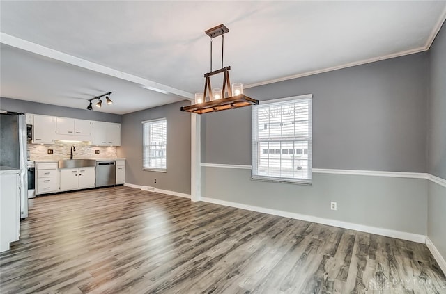 kitchen with sink, wood-type flooring, decorative light fixtures, stainless steel appliances, and white cabinets